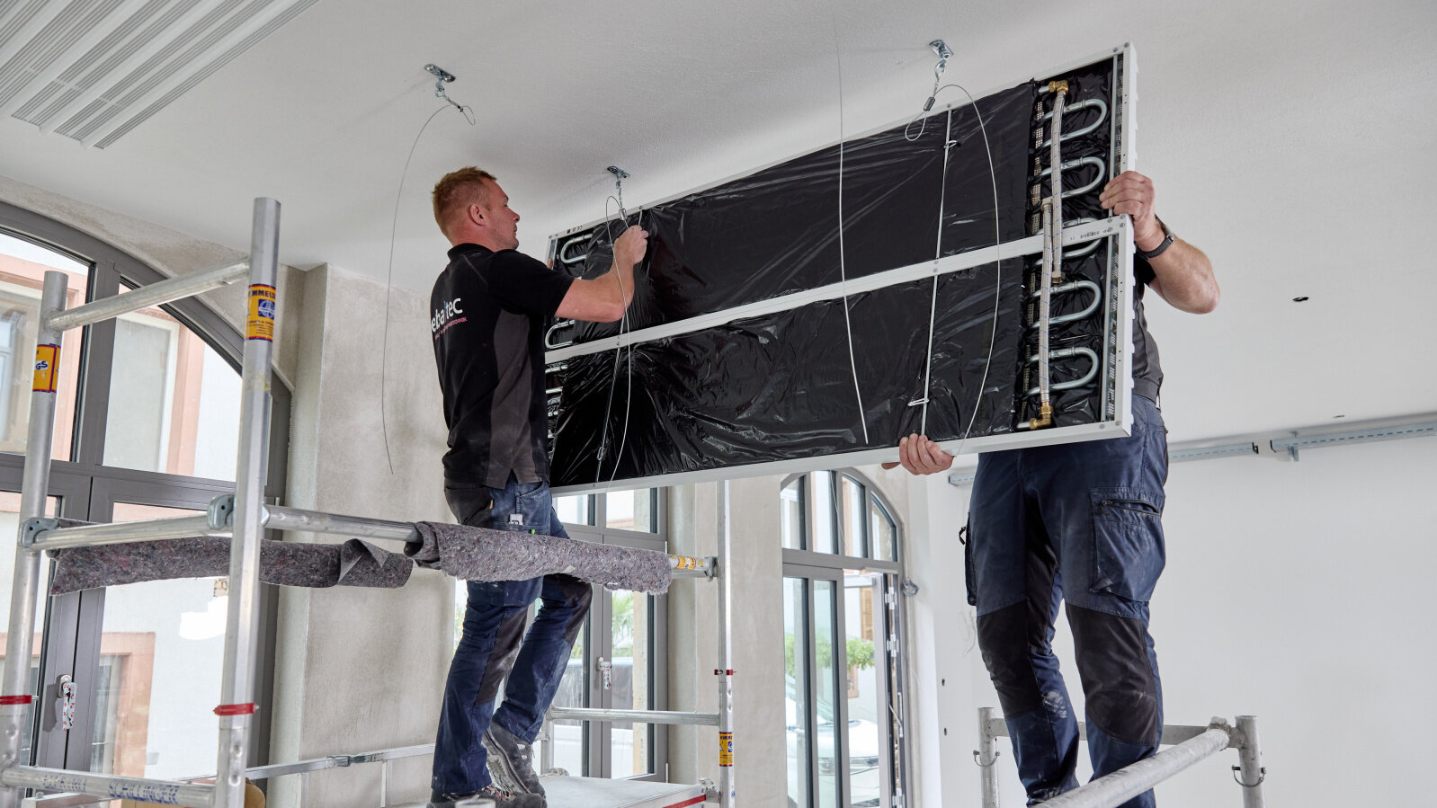  Zwei Monteure installieren leichte Strahlplatte an der Decke