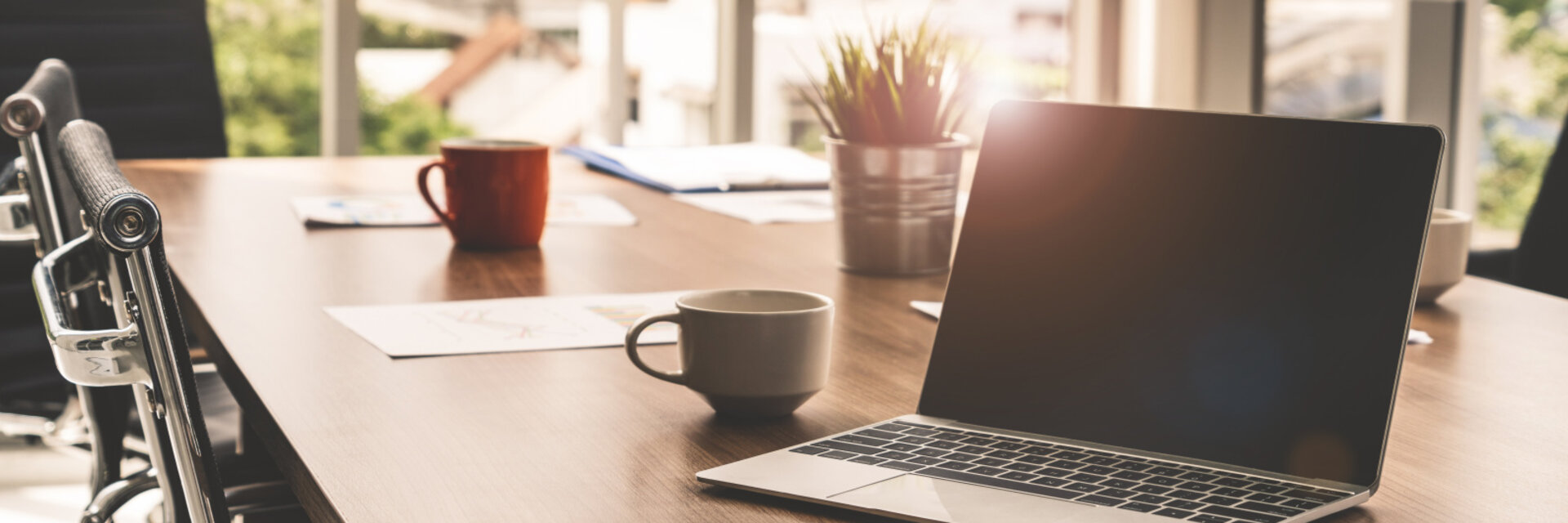 Laptop computer with opened lid on table in meeting room of office workspace.